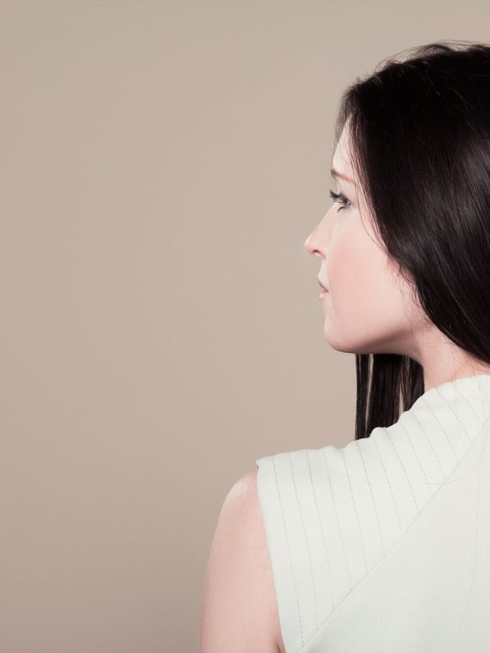 Mulher elegante de perfil, com cabelo escuro e liso impecável
